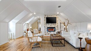 A spacious loft with a stone wall, a fireplace, and a flat-screen TV. - Peri Social House (Black Mountain)