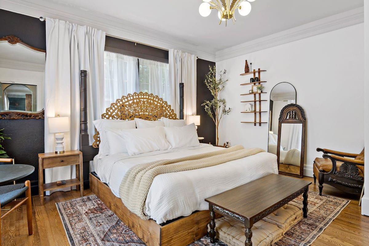A well-appointed bedroom with a large bed, bedside tables, a wooden bench, and a mirror.