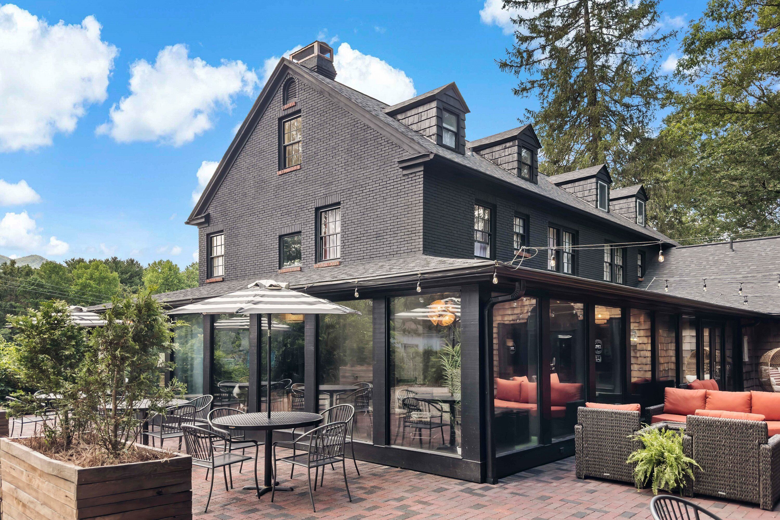 Una casa moderna con un amplio patio que cuenta con mobiliario exterior y un espacio comedor con cerramiento de vidrio.