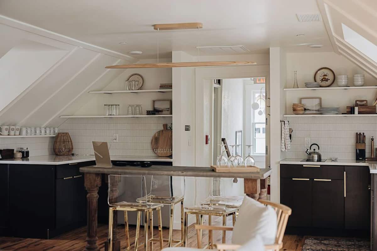 A modern kitchen with a central island, bar stools, and a dining area with a white table and chairs.