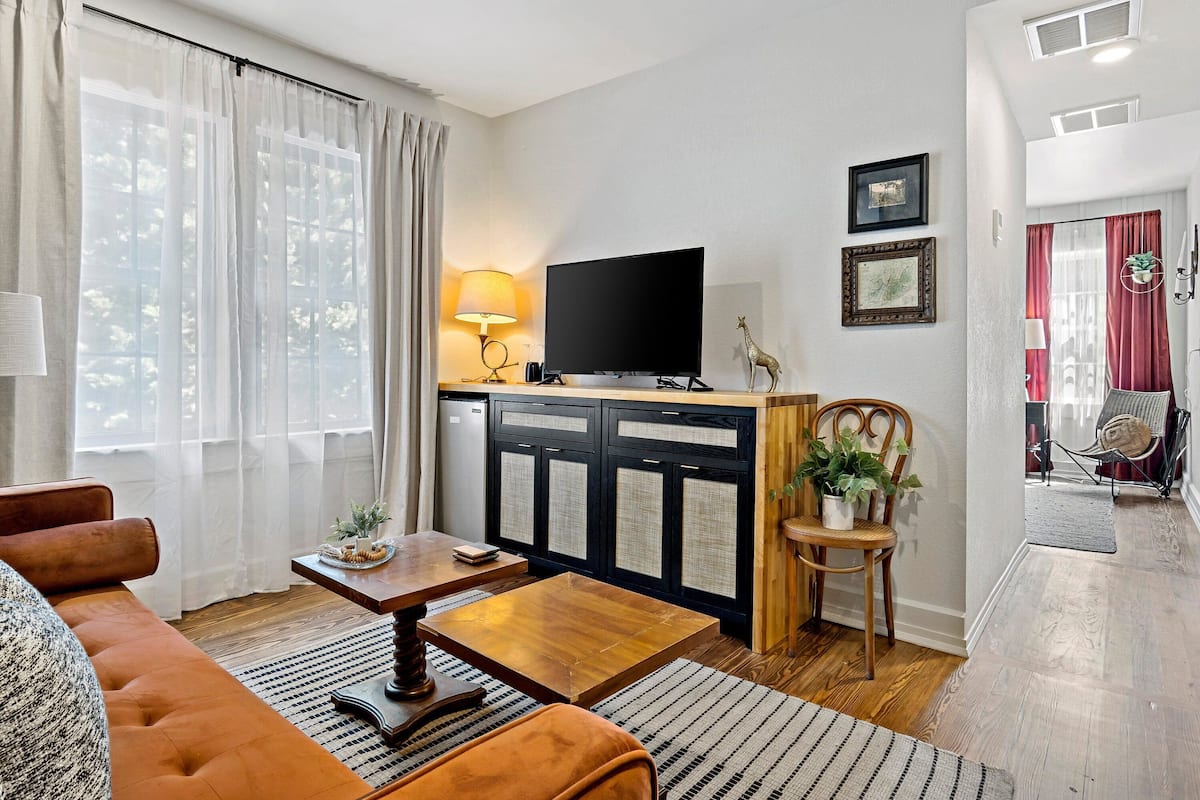 A living room with a sofa, coffee table, TV, and a small dining area.