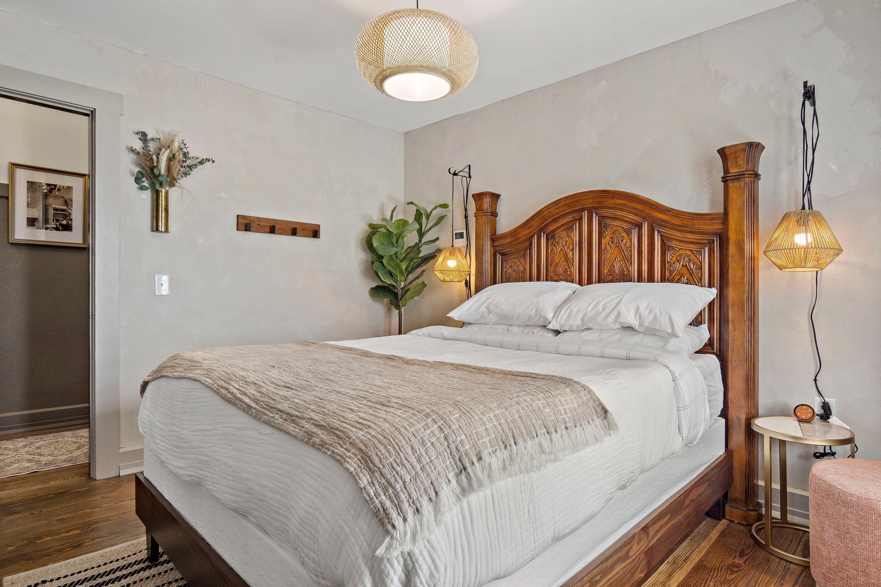 A neatly made bed with a wooden headboard, a bedside lamp, and a small table with a clock.