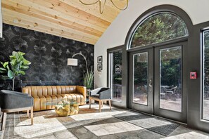 Eine moderne Lobby mit Holzboden, einer Wand mit Schwarzmuster, einer Ledersofa, einem Glastisch und einem großen Bogenfenster.