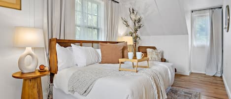 A neatly arranged bedroom with a large bed, bedside tables, and a decorative plant.