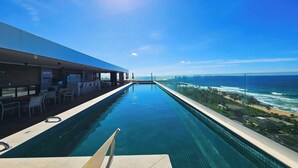 Una piscina larga con vistas al océano y a la playa.