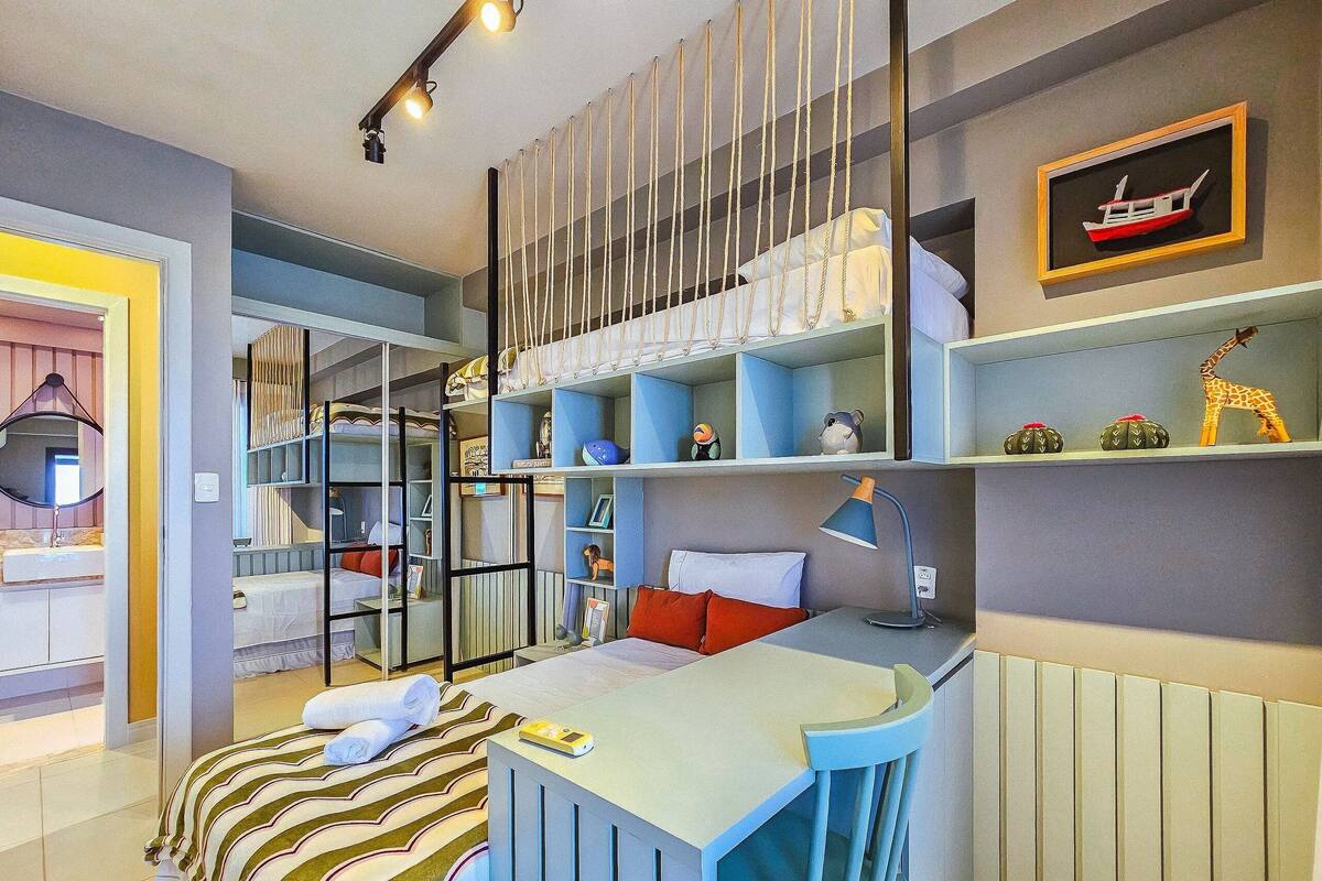 Un dormitorio infantil con cama, escritorio y estanterías llenas de juguetes y adornos.