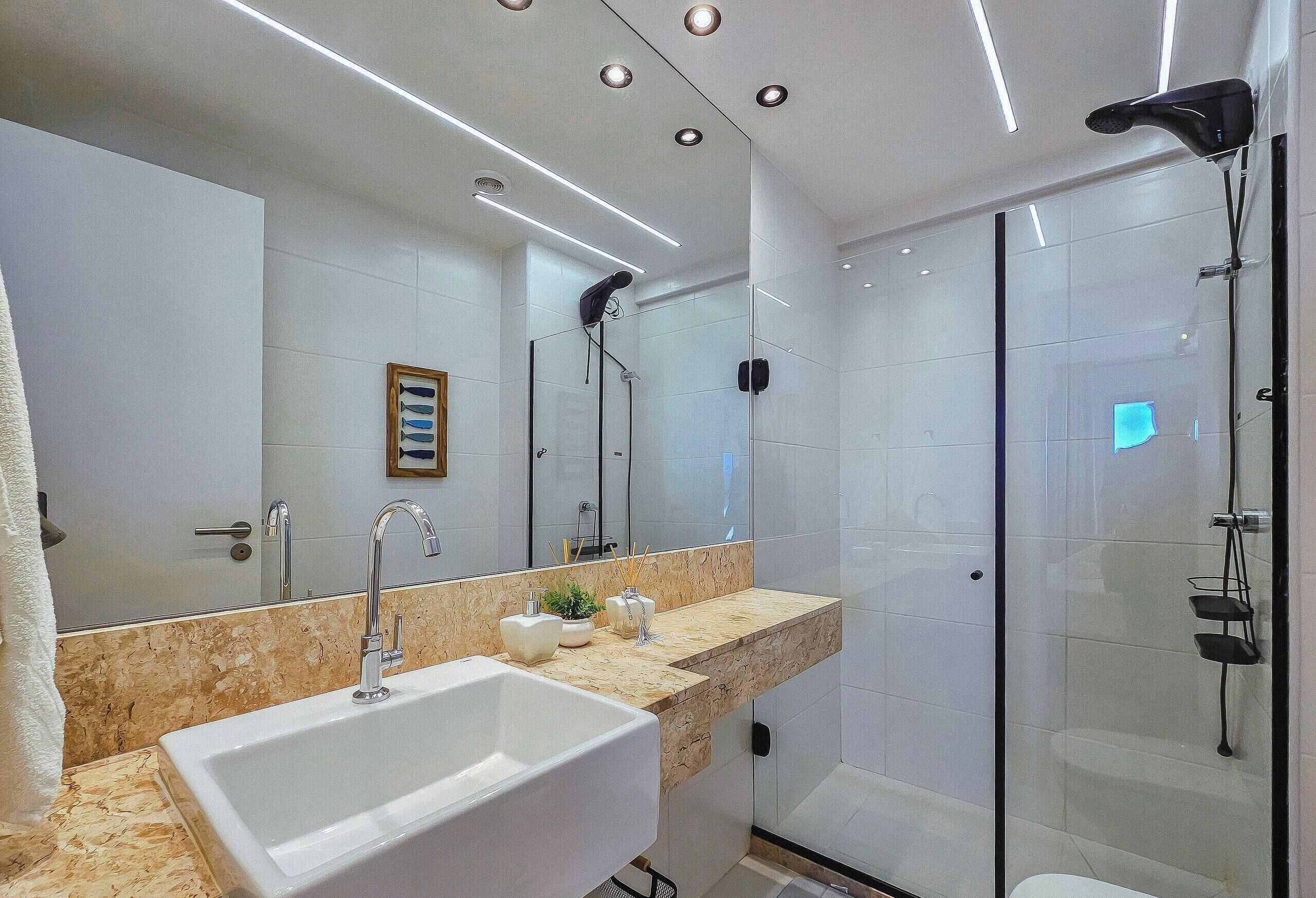A modern bathroom with a large sink, mirror, and glass shower enclosure.