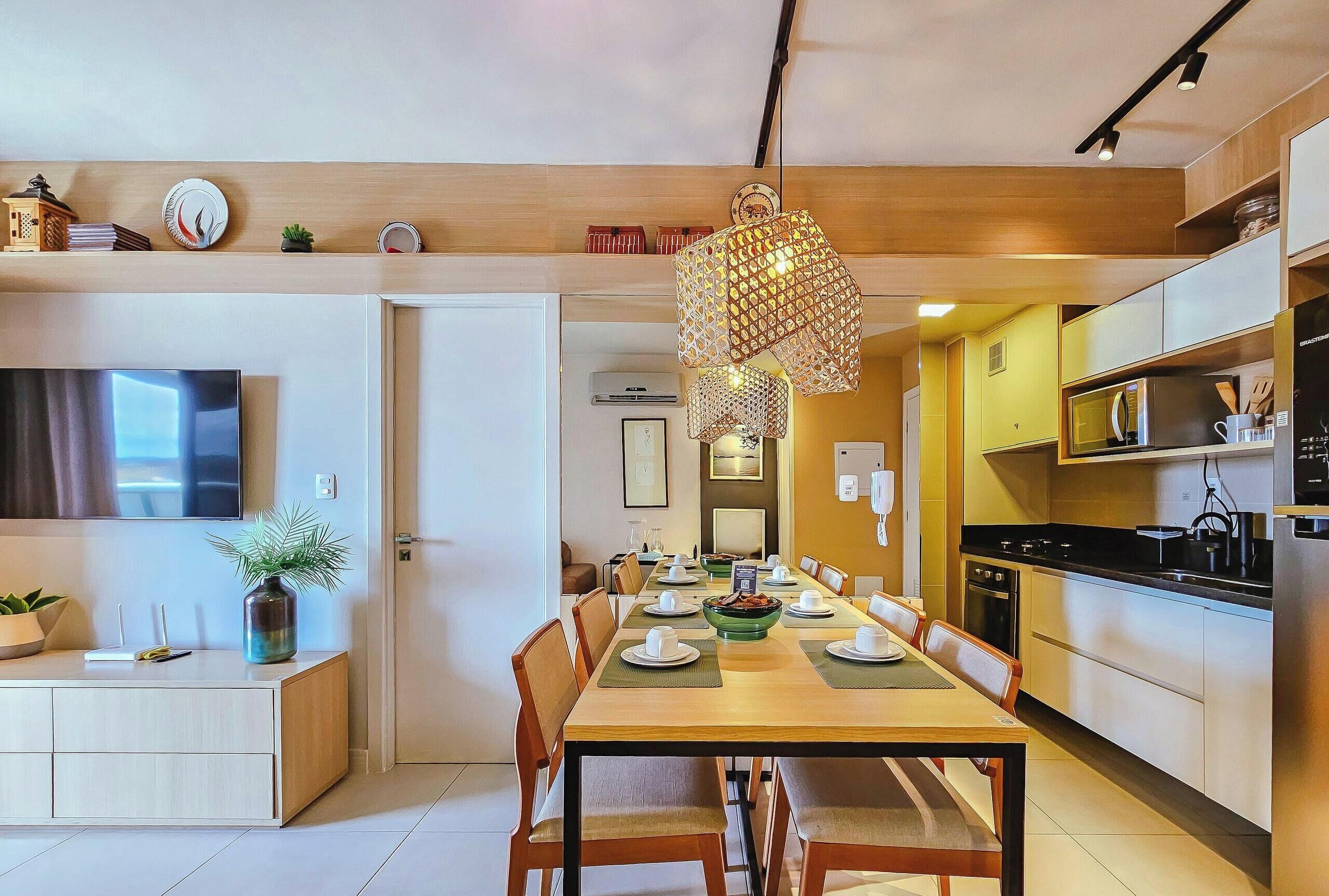 A modern kitchen with a dining area, wooden cabinets, and a hanging light fixture.