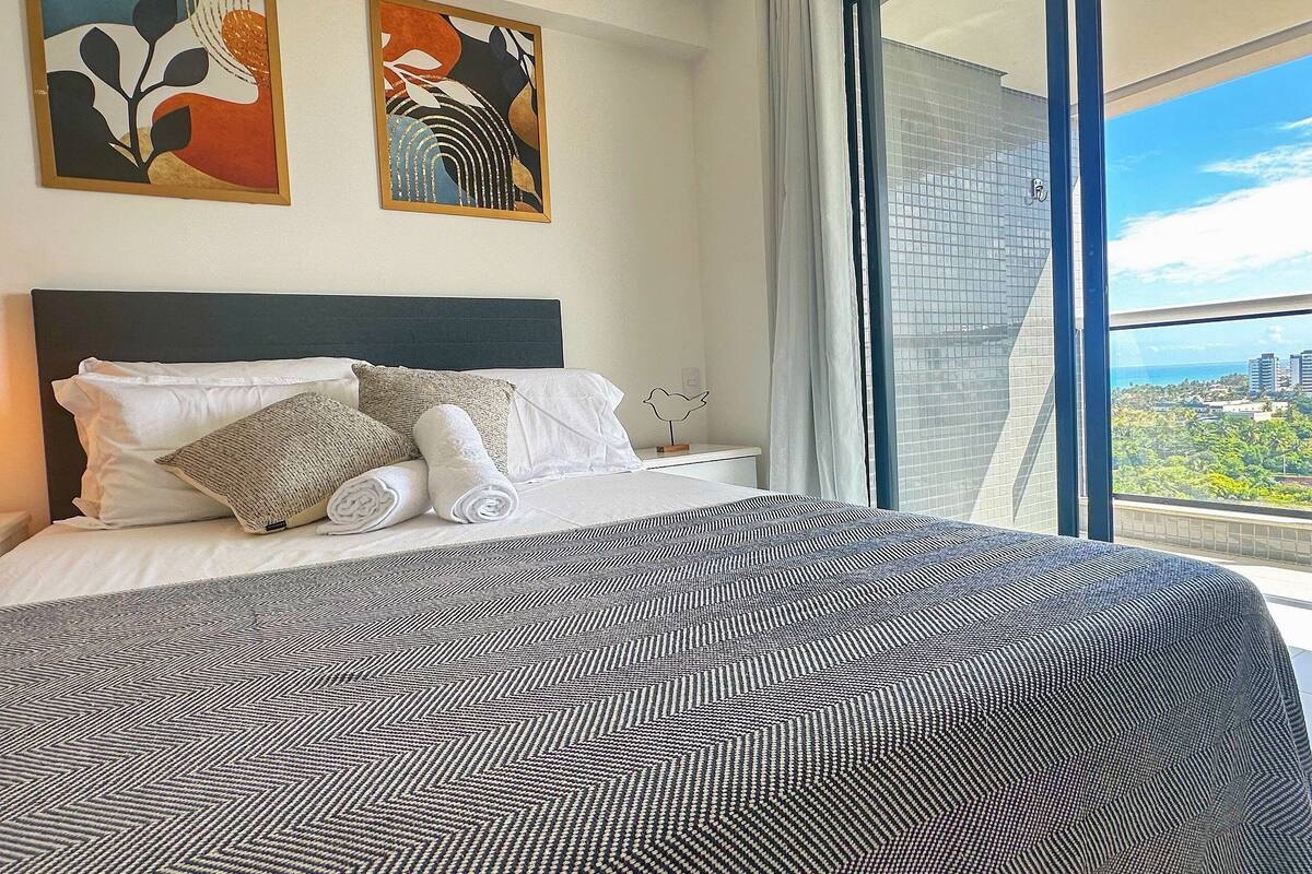 Habitación de hotel con una cama grande, vistas a la ciudad y arte abstracto en la pared.