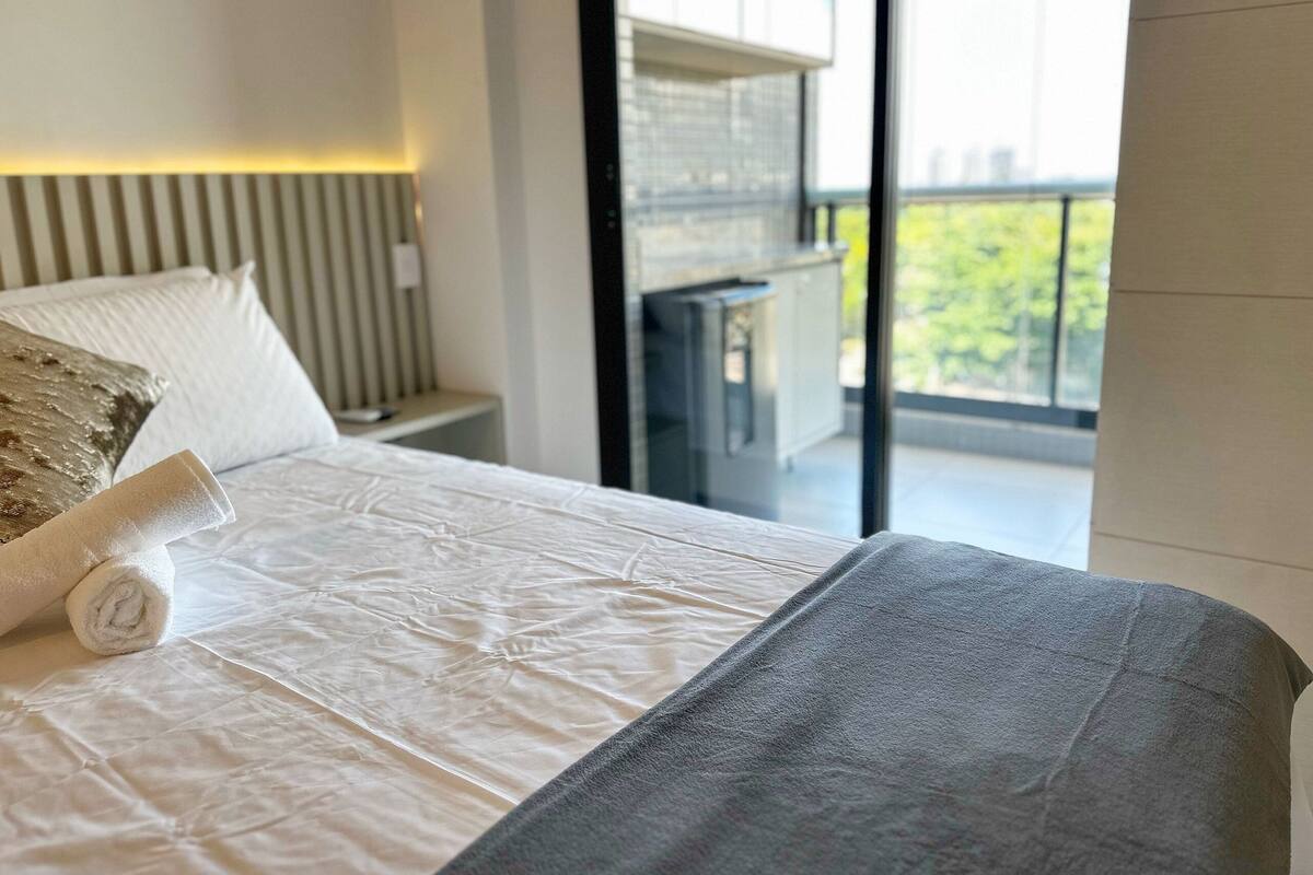 Una habitación de hotel moderna con una cama grande, vistas al exterior y un balcón.
