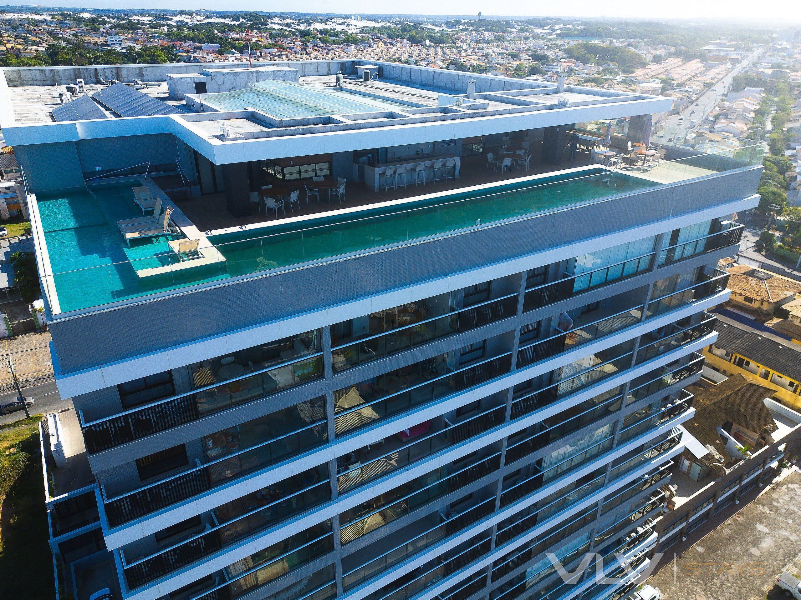Un edifici alt amb piscina al terrat i múltiples balcons.