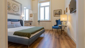 A bedroom with a bed, a chair, a table, and a window. - Studio San Michele by Wonderful Italy (Turin)