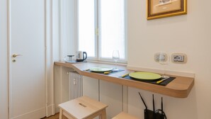 A kitchen with a window, a radiator, a framed picture, and a small table. - Studio San Michele by Wonderful Italy (Turin)
