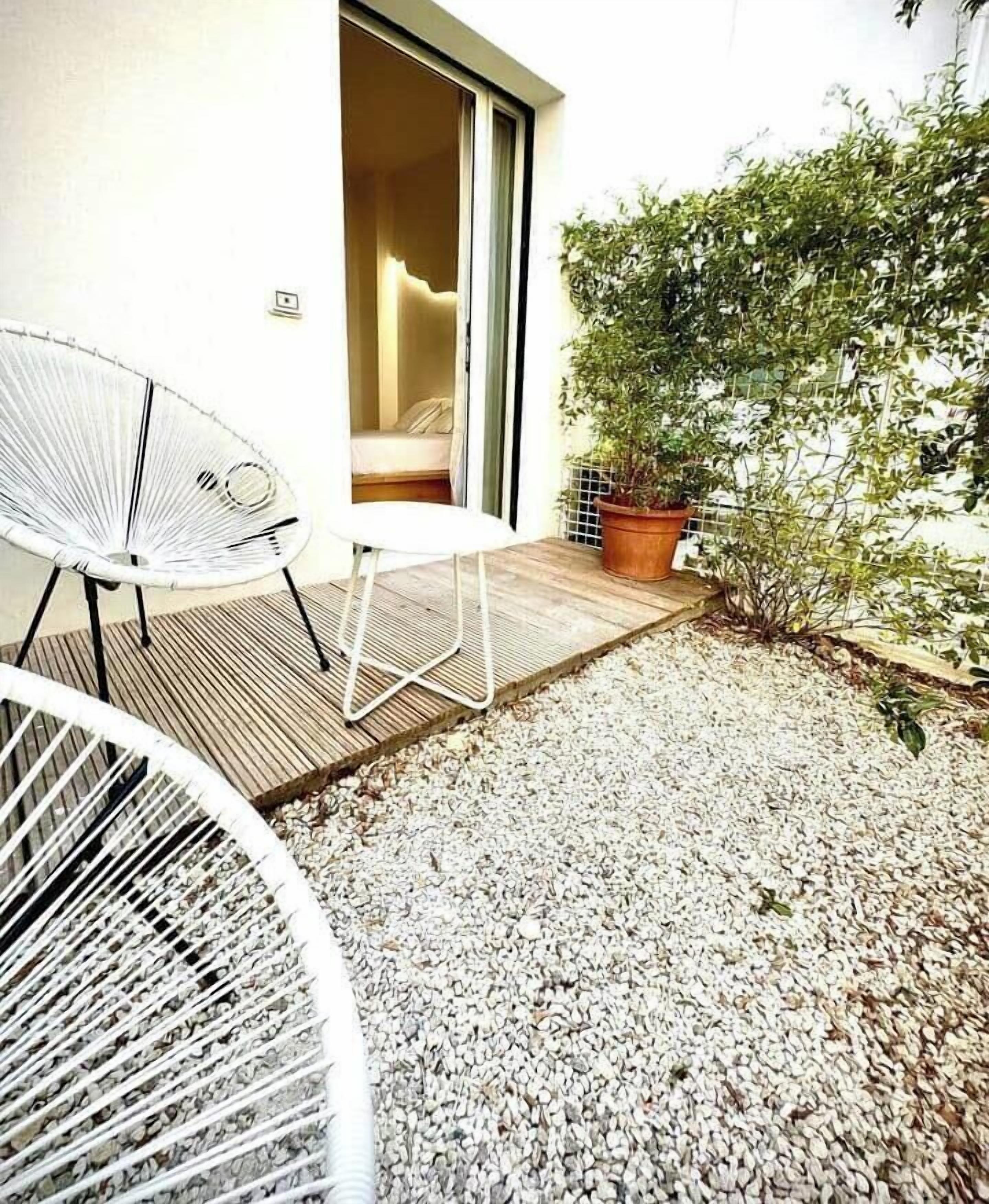 A patio with a white chair, a small table, and a potted plant.