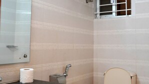 Une salle de bain avec des toilettes, un lavabo et une fenêtre avec des barreaux.