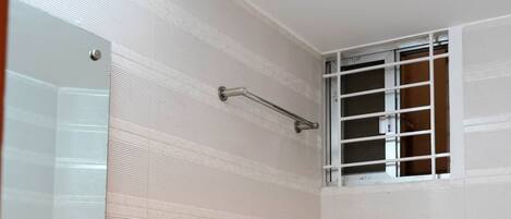 Un baño con inodoro, lavabo y ventana con barrotes.