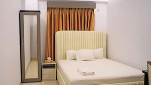 Une chambre à coucher avec un lit, une table de chevet, un miroir et une fenêtre avec des rideaux.