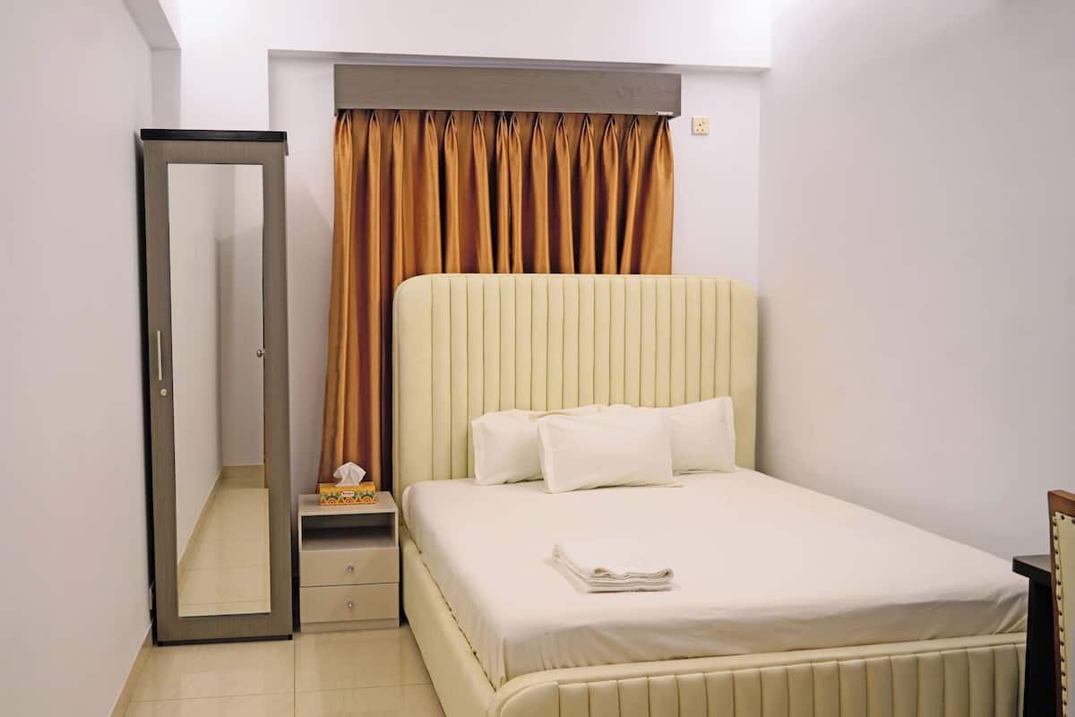 Une chambre à coucher avec un lit, une table de chevet, un miroir et une fenêtre avec des rideaux.