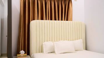 A hotel room with a large bed, a headboard, and a curtain.