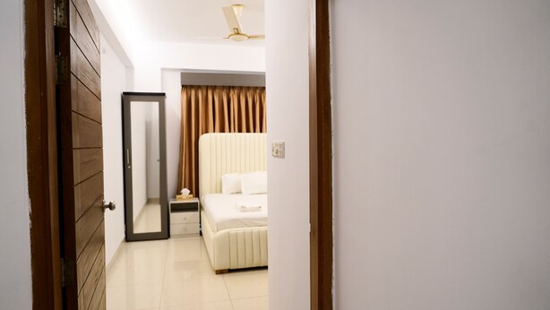 Une chambre d’hôtel avec un lit, une table de chevet, un miroir et un ventilateur de plafond.