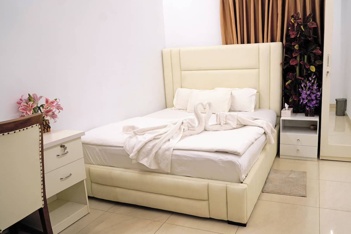 Une chambre à coucher bien rangée, avec un lit, des tables de chevet, une commode et un miroir.