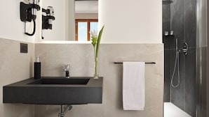 Een moderne badkamer met een zwart wastafel, een douchecabine van glas en een witte handdoek op een handdoekhouder.