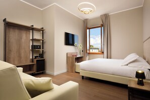 A modern hotel room with a bed, a desk, a TV, and a view of the city. - Essence Hotel (Florence)