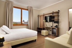 A hotel room with a bed, a desk with a TV, a coffee machine, and a view of a cityscape. - Essence Hotel (Florence)