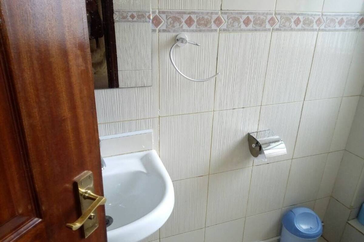A bathroom with a sink, a toilet paper holder, and a trash bin.