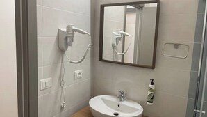Une salle de bain équipée d’un lavabo, d’un miroir et d’une douche fixée au mur.