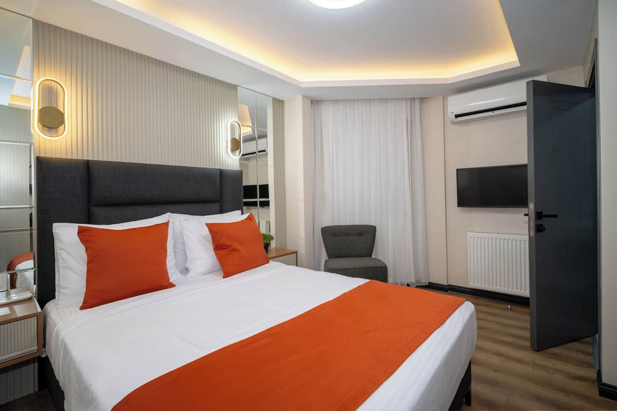 A hotel room with a large bed, a chair, a TV, and a door.