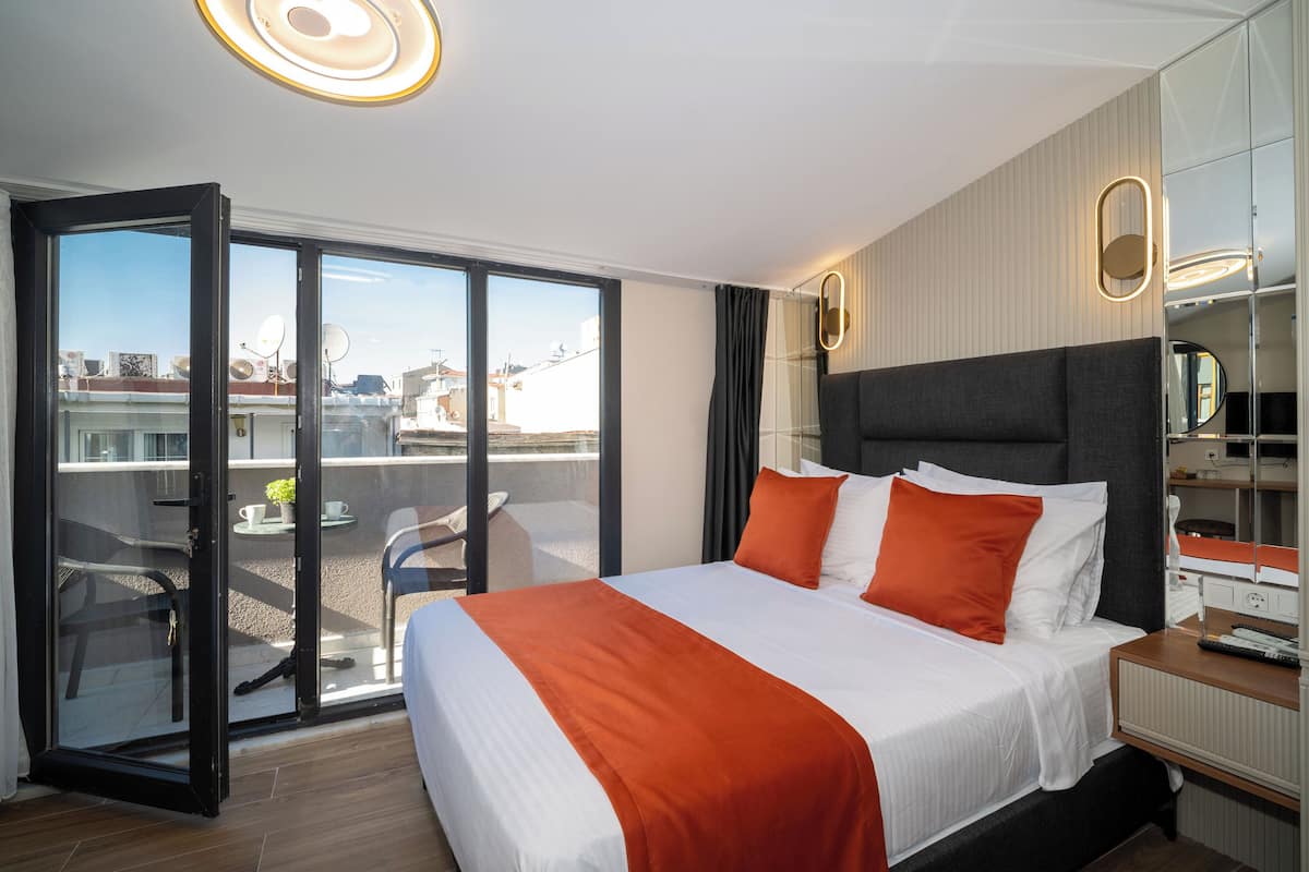 A hotel room with a large bed, a sliding glass door to an outdoor area, a bedside table with a lamp, and a mirror.