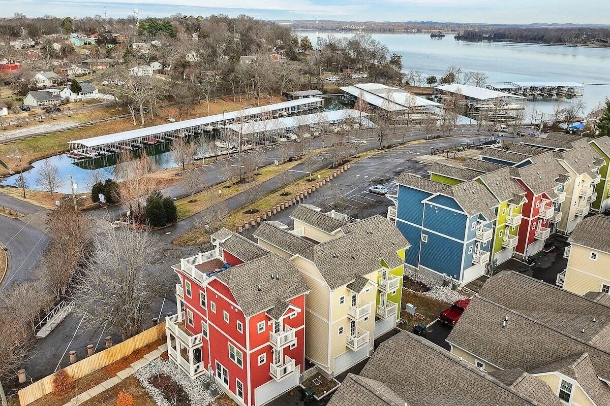 Een woonwijk met kleurrijke huizen, een steiger en een waterlichaam op de achtergrond.