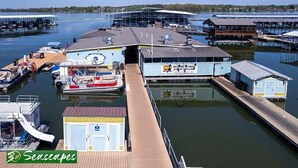 Un port esportiu amb vaixells amarrats, un edifici petit amb un rètol i un moll de fusta.