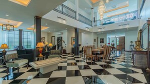 A spacious lobby with a checkered floor, a dining area, and a staircase leading to an upper level. - Villa Viola | Fully staffed New Luxury Villa | Laguna Golf Course & Beach Access (Pa Sak)