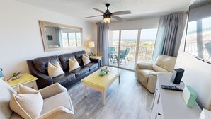 A modern living room with a sofa, armchairs, a coffee table, and a ceiling fan. - Gulf Dunes 102 3 Bedroom Condo by RedAwning (Fort Walton Beach)