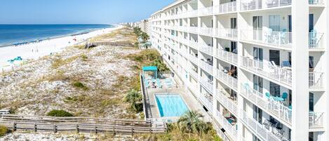 A beachfront hotel with multiple balconies, a swimming pool, and a beach view.