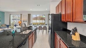 A modern kitchen with a central island, stainless steel appliances, and wooden cabinets. - Upstay: Resort Villa w Pool & Cinema near Disney (Kissimmee)