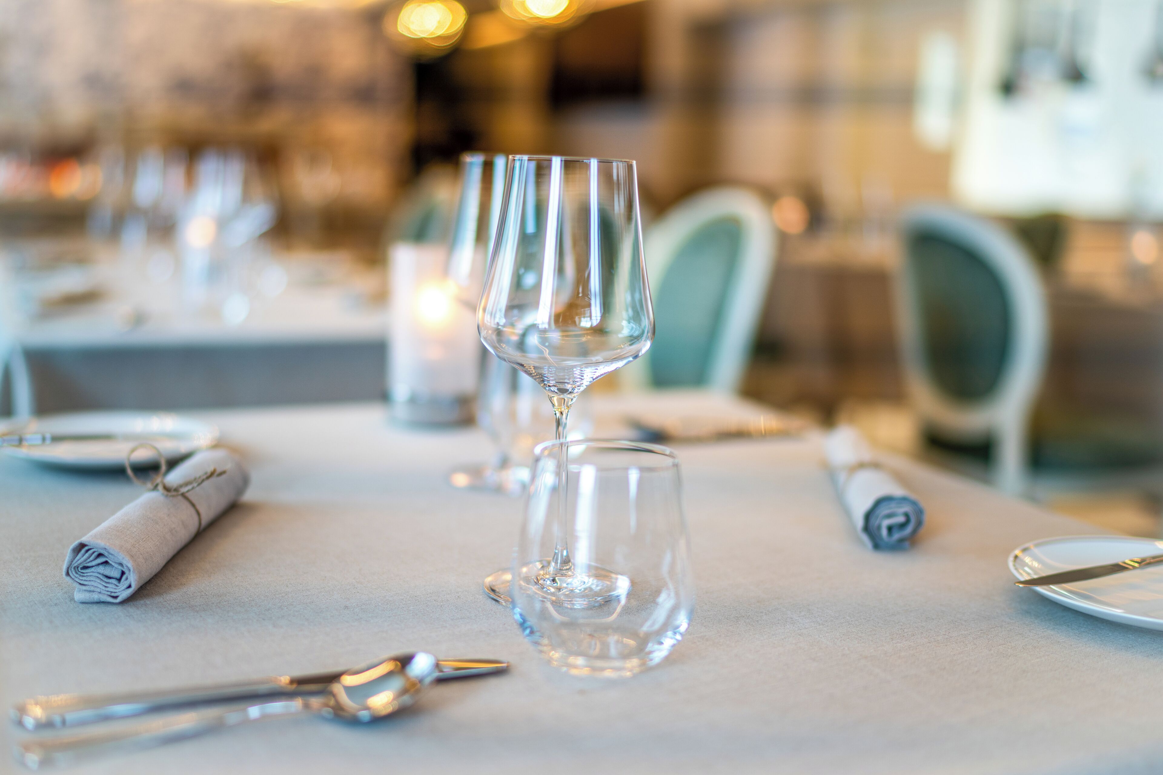 A dining table with empty wine glasses, a rolled napkin, and cutlery.
