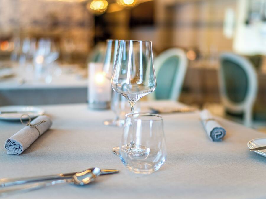 A dining table with empty wine glasses, a rolled napkin, and cutlery.