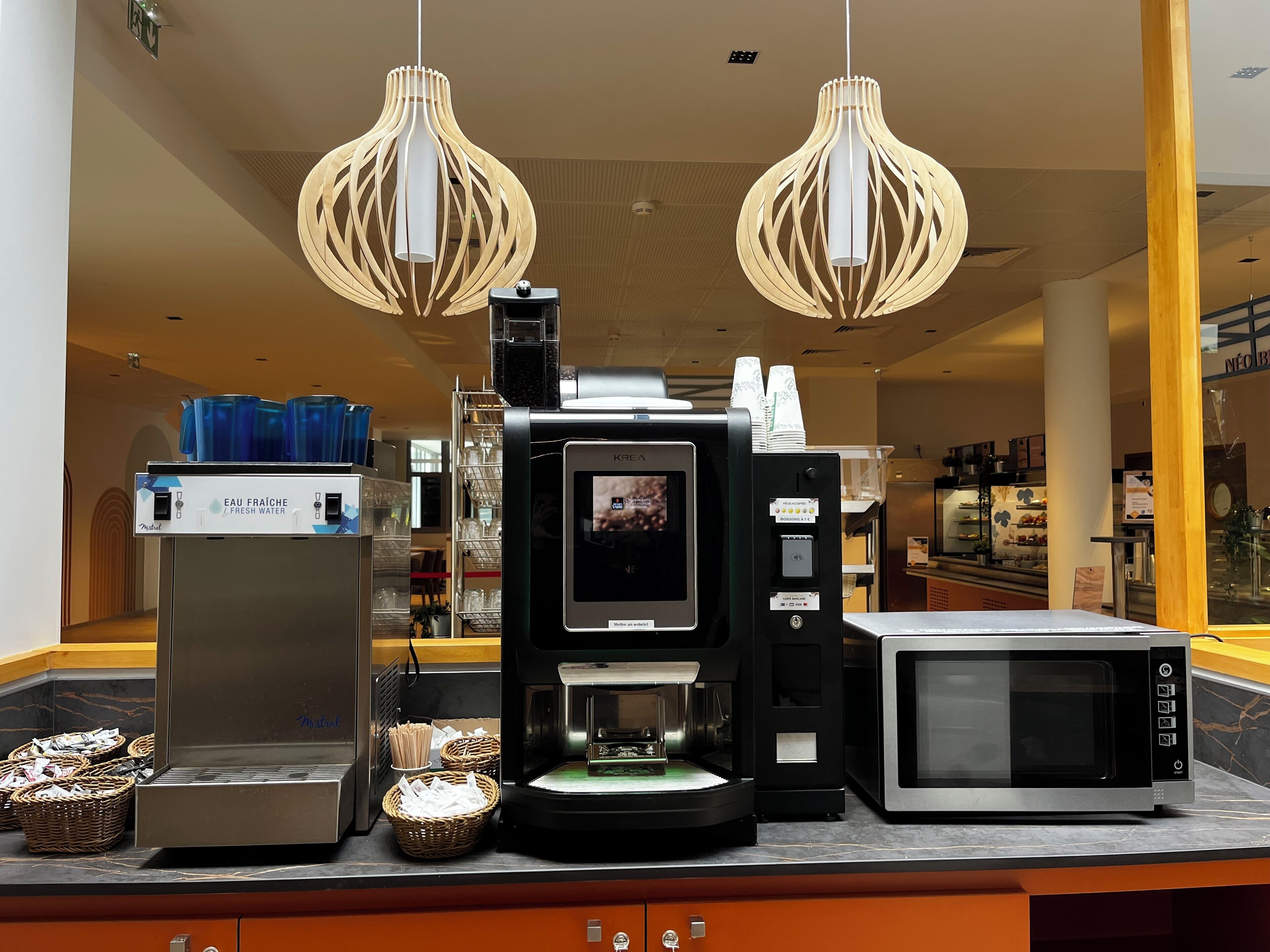 A coffee machine, a water dispenser, and a microwave on a counter.