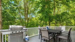 A deck with a grill, table, and chairs, surrounded by trees. - 5 mins to Acadia and 5 min walk to town! (Southwest Harbor)