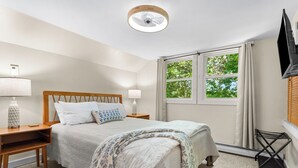 A bedroom with a bed, bedside tables, a lamp, a ceiling fan, a window with curtains, and a TV mounted on the wall. - 5 mins to Acadia and 5 min walk to town! (Southwest Harbor)