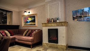 A living room with a sectional sofa, a fireplace, a framed floral painting, and a cityscape picture on the wall. - Comfort Home Taksim (Istanbul)
