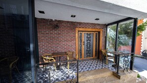 A brick exterior with a glass door and windows, outdoor seating with wicker chairs and a wooden table, and a tiled floor. - Comfort Home Taksim (Istanbul)