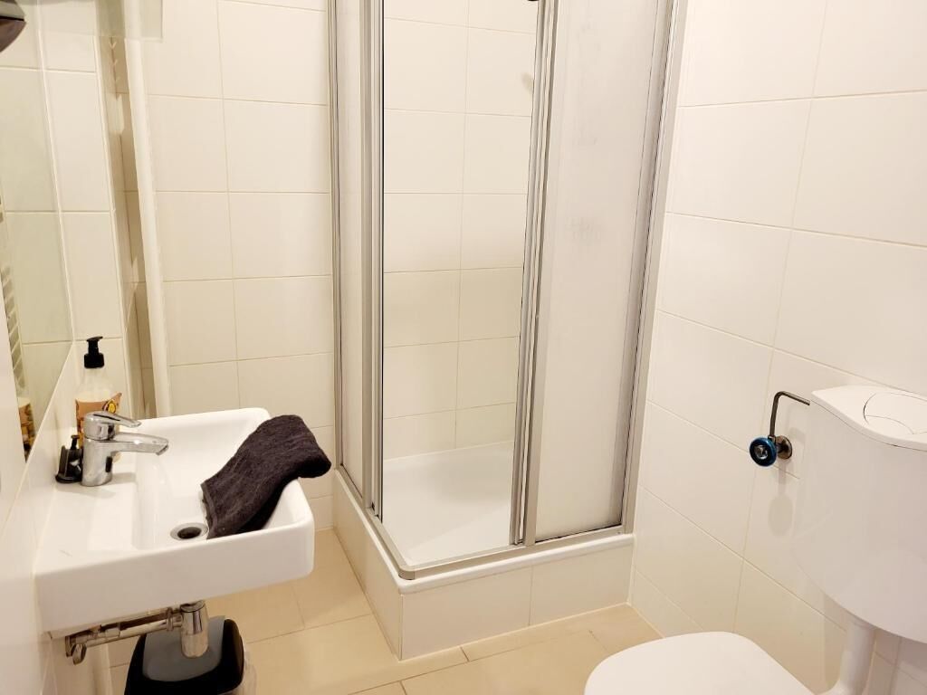 A bathroom with a white sink, a glass shower enclosure, and a toilet.