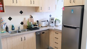 A modern kitchen with wooden cabinets, a stainless steel dishwasher, a Samsung refrigerator, a coffee maker, and a toaster. - Tranquil, Stylish, Retreat - 3 Bedrooms (Tuncurry)