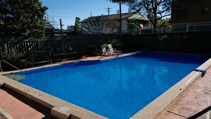 A rectangular swimming pool with a clear blue water surface, surrounded by a tiled deck and a metal fence. - Tranquil, Stylish, Retreat - 3 Bedrooms (Tuncurry)