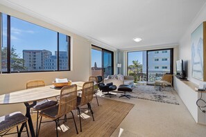 Una habitación de hotel moderna con zona de comedor, sofá y televisor.