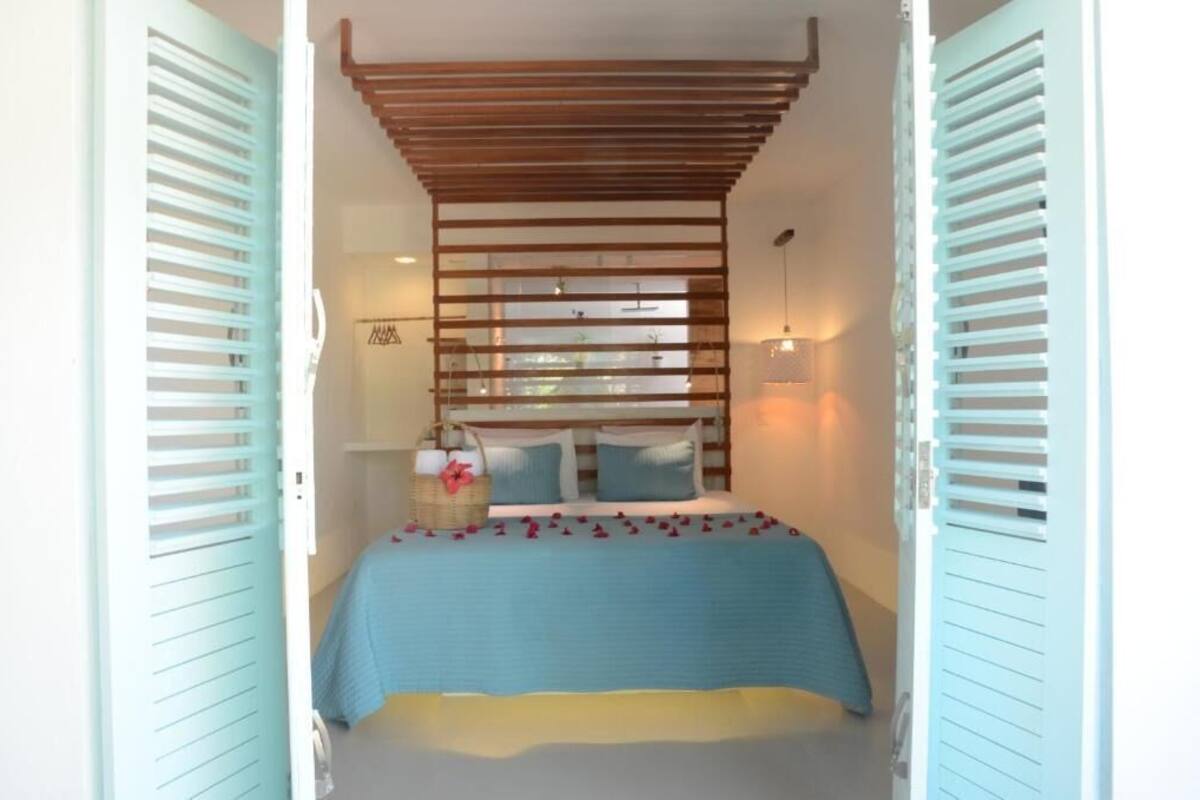 A bedroom with a bed, a wooden slatted headboard, and a basket on the nightstand.